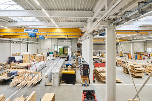 Industriehalle des Projekts Bropack mit integrierter Holzbox-Fertigung, klar gegliederten Produktionszonen und leistungsfähiger Kraninfrastruktur – architektonisch geplant von arcplus