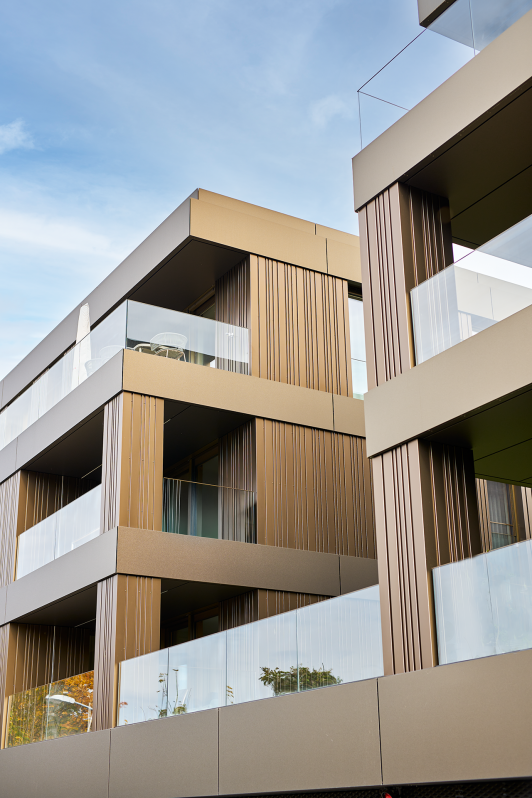 Detail einer modernen Wohnfassade mit vertikalen Metalllamellen, Balkonen und Glasgeländern. geplant und umgesetzt von arc plus Freudenstadt