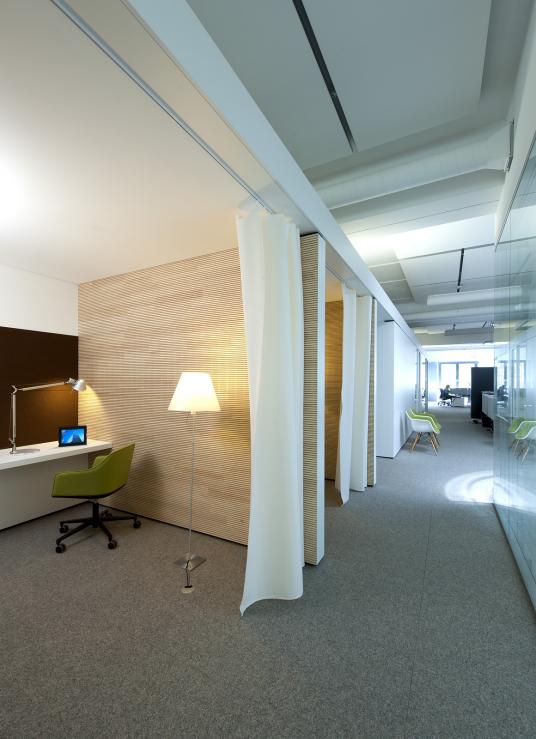 Sanierte Bürofläche bei Hansgrohe in Schiltach mit textilen Raumteilern, Holzverkleidung und integrierten Einzelarbeitsplätzen für konzentriertes Arbeiten – geplant von arcplus aus Freudenstadt
