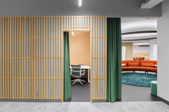 Flexible Rückzugsnische im Hansgrohe FlexWork Schiltach mit Holzlamellenwand, Vorhang und integrierter Arbeitsstation sowie angrenzender Loungezone – geplant von arc plus Freudenstadt