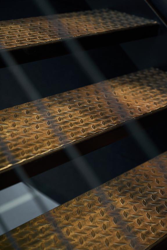 Detailaufnahme einer industriellen Stahltreppe mit rutschhemmendem Tränenblech im Logistik- und Verwaltungsgebäude der SHW Logistik und Vertrieb GmbH, Hersteller von Schmiedeprodukten, Handwerkzeugen sowie Lösungen für Garten-, Forst-, Landwirtschafts- und Kommunaltechnik, in Freudenstadt. Bauherr: SHW Logistik und Vertrieb GmbH. Geplant und umgesetzt von arc+ GmbH Freudenstadt.